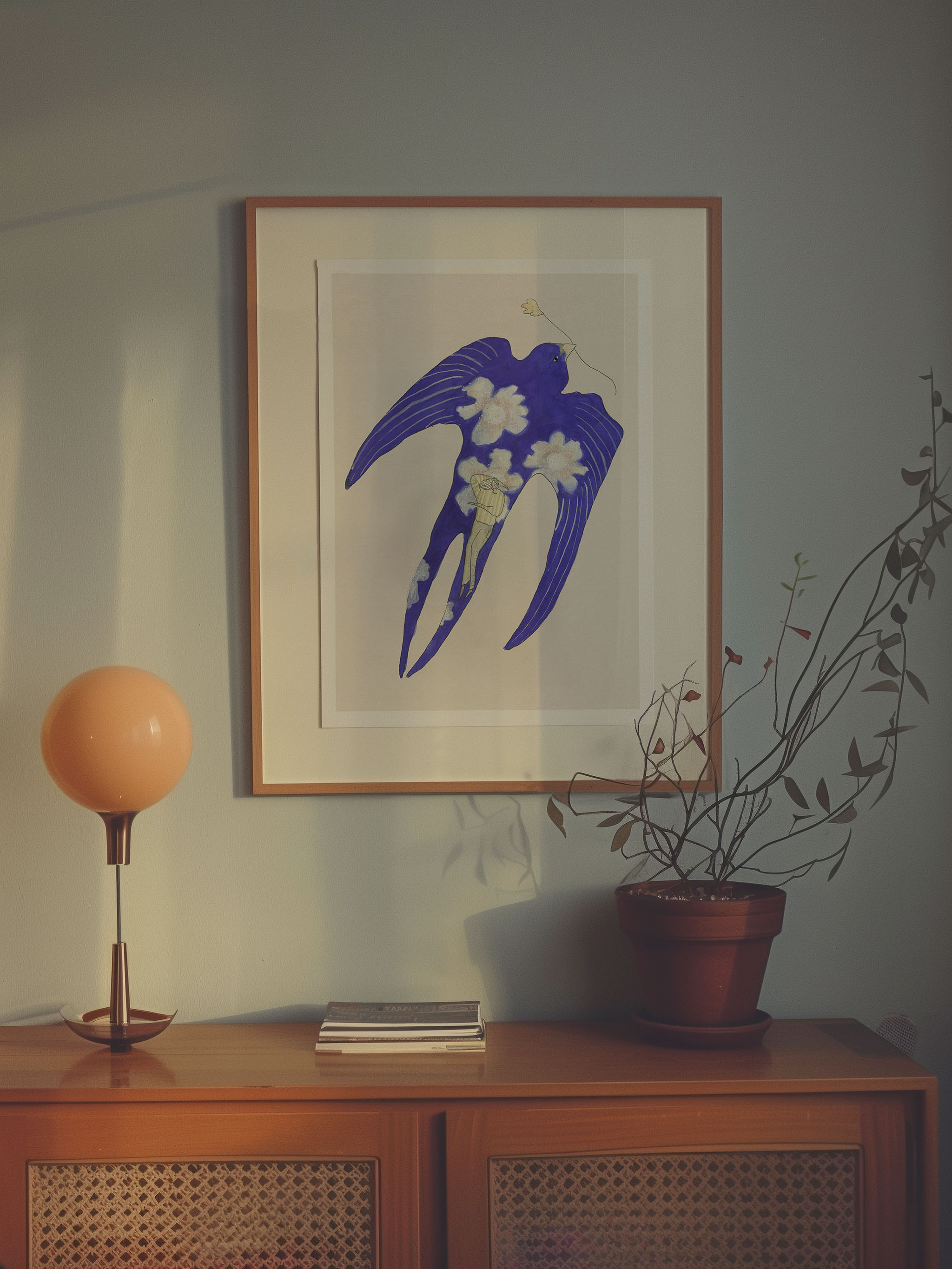 Dagdrømmeren kunstplakat med blå fugl og hvide blomster over en trækommode
