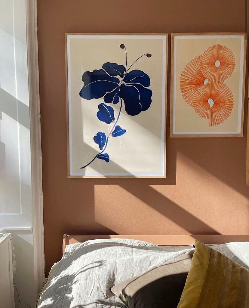 Harmonisk soveværelse indretning med papir vifte plakat af Andrea Krull og blåt blomsterprint.