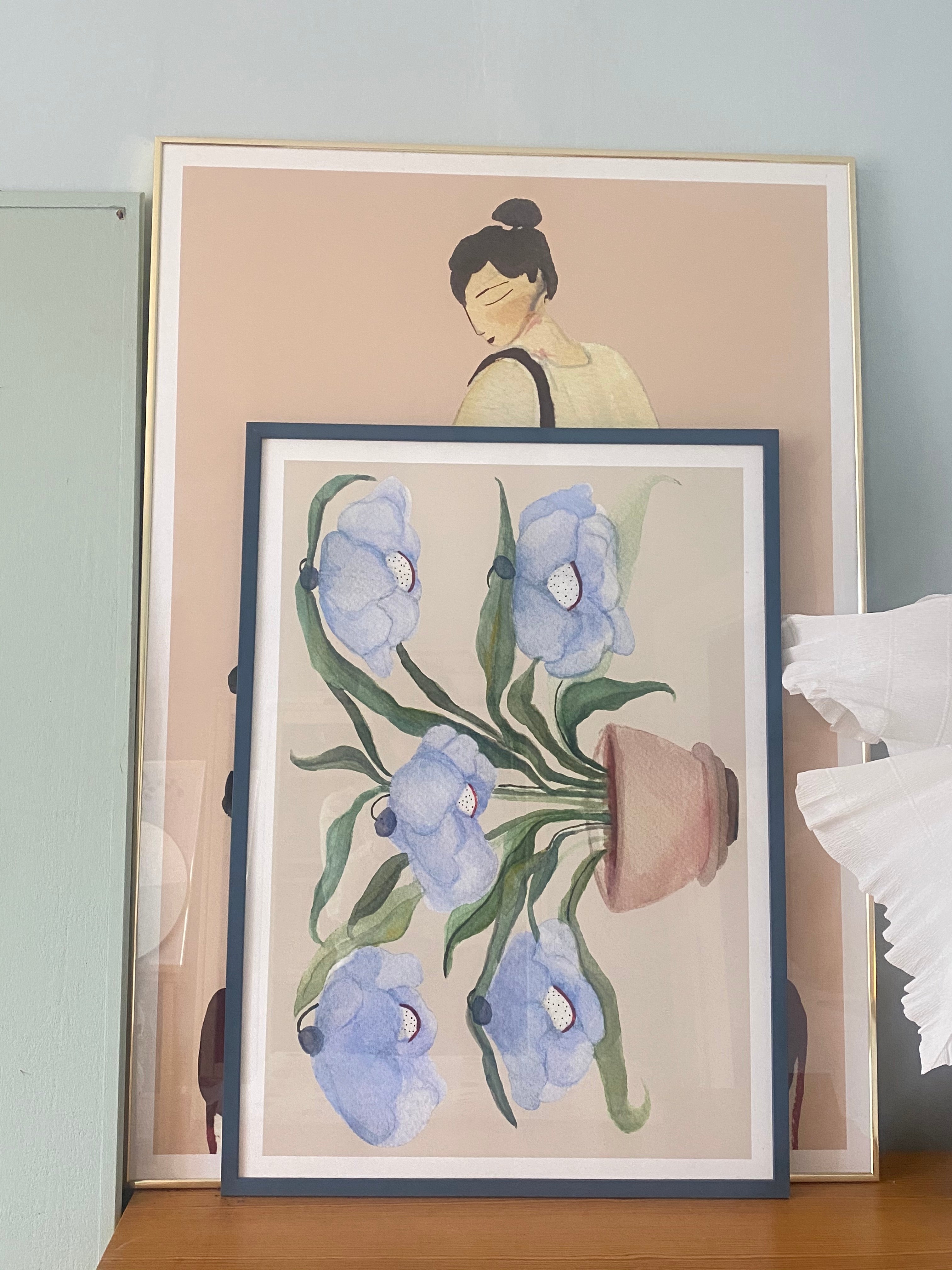 DESERT BLUEBELLS kunstplakat i mørkeblå ramme på kommode foran stort figurmotiv