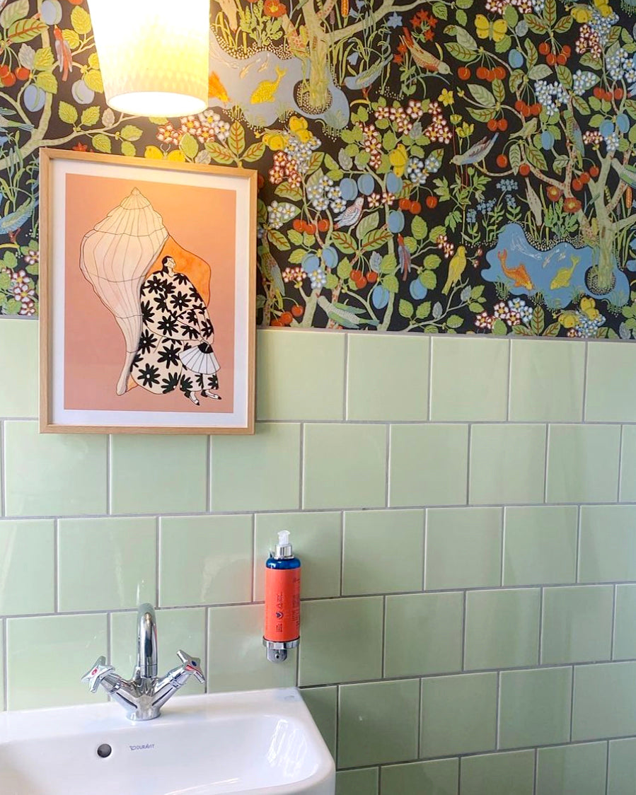 SEASHELL SOUNDS kunstplakat i lys træramme over håndvask med grønne fliser og blomstret tapet