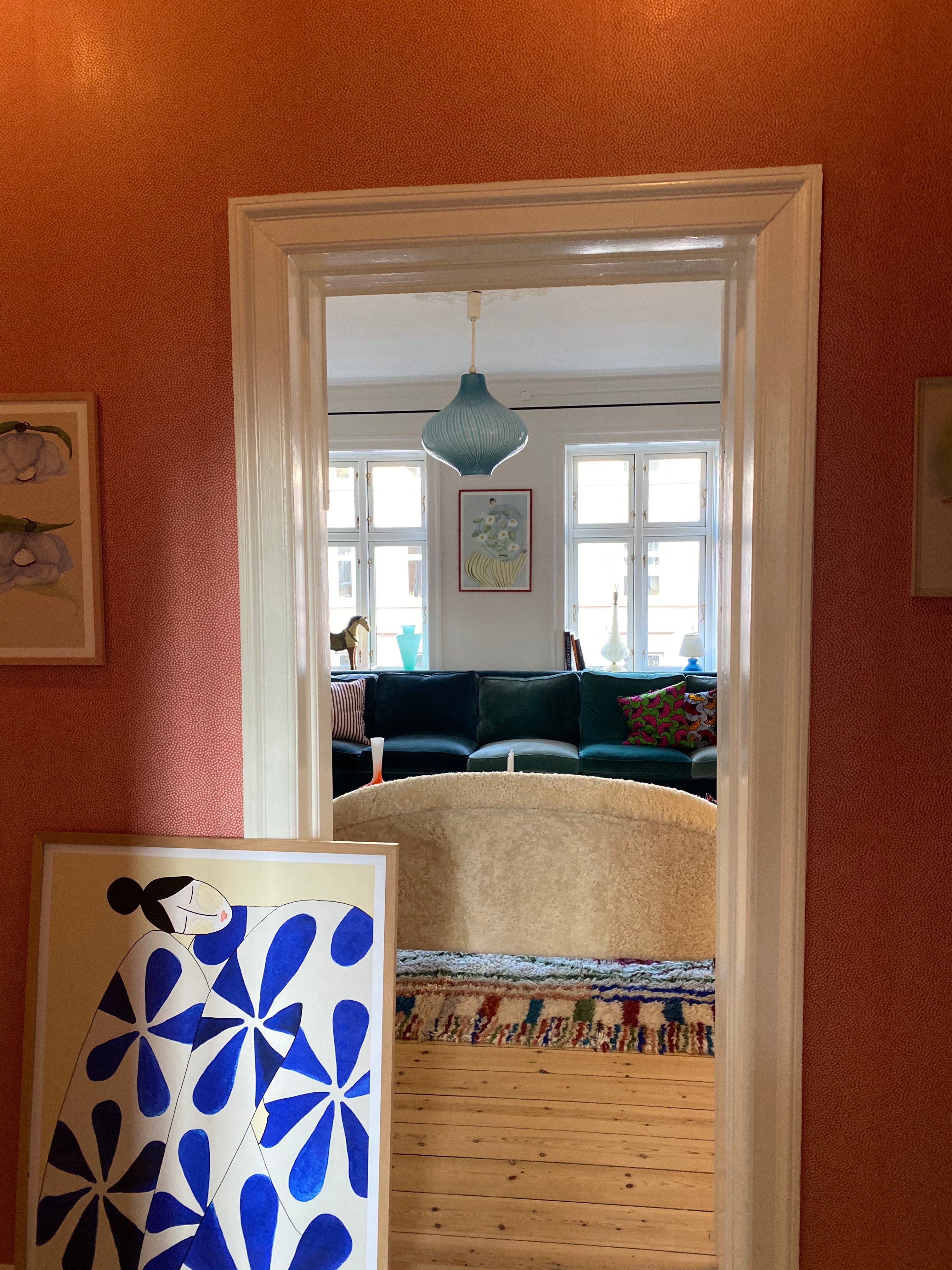 Kunstplakat med blå dame af Andrea Krull set gennem en hvid døråbning i en lys og nordisk