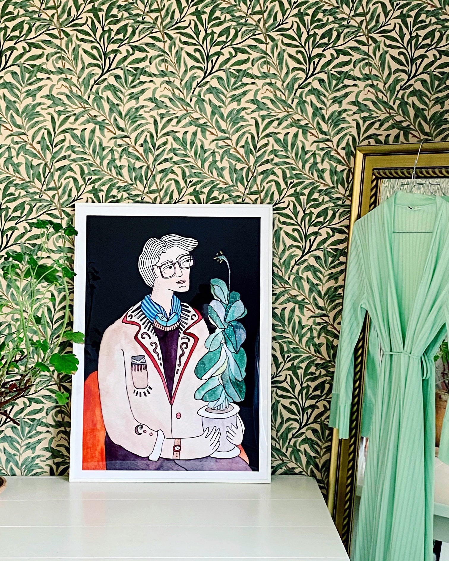 THE FIDDLE LEAF GUY kunstplakat i hvid ramme på bord foran grønt bladtapet og spejl