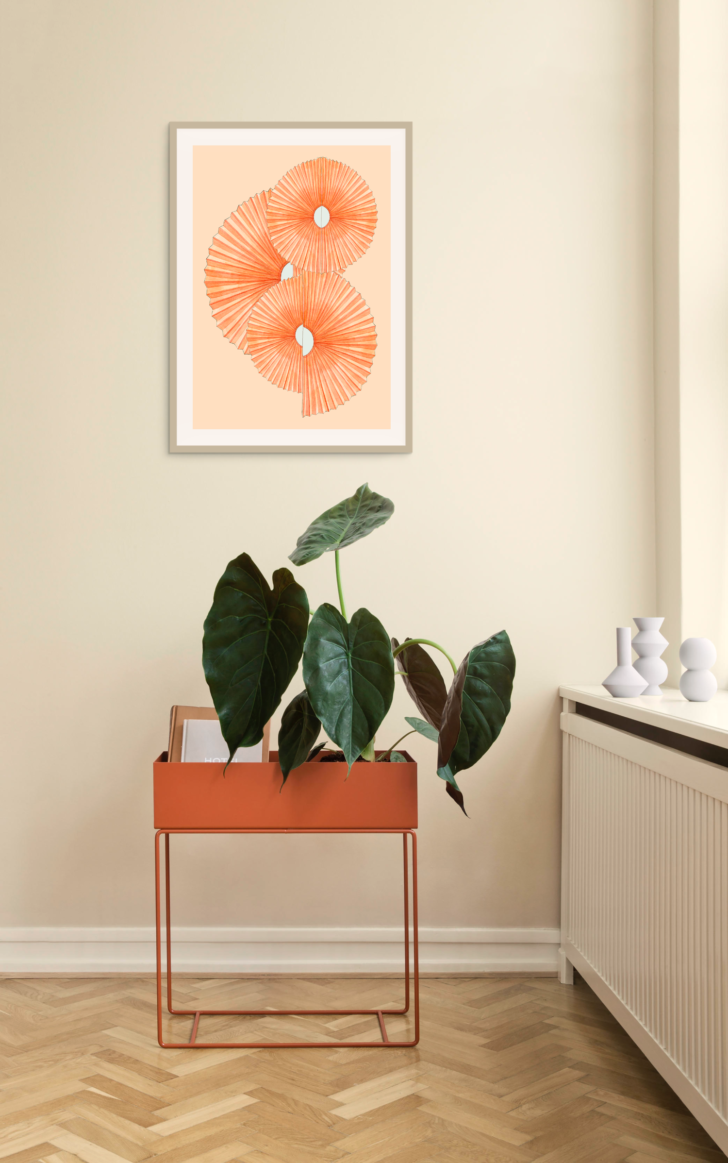 Orange kunsttryk Paper Fans af Andrea Krull hængt op over en moderne plantekasse i en lys gang.