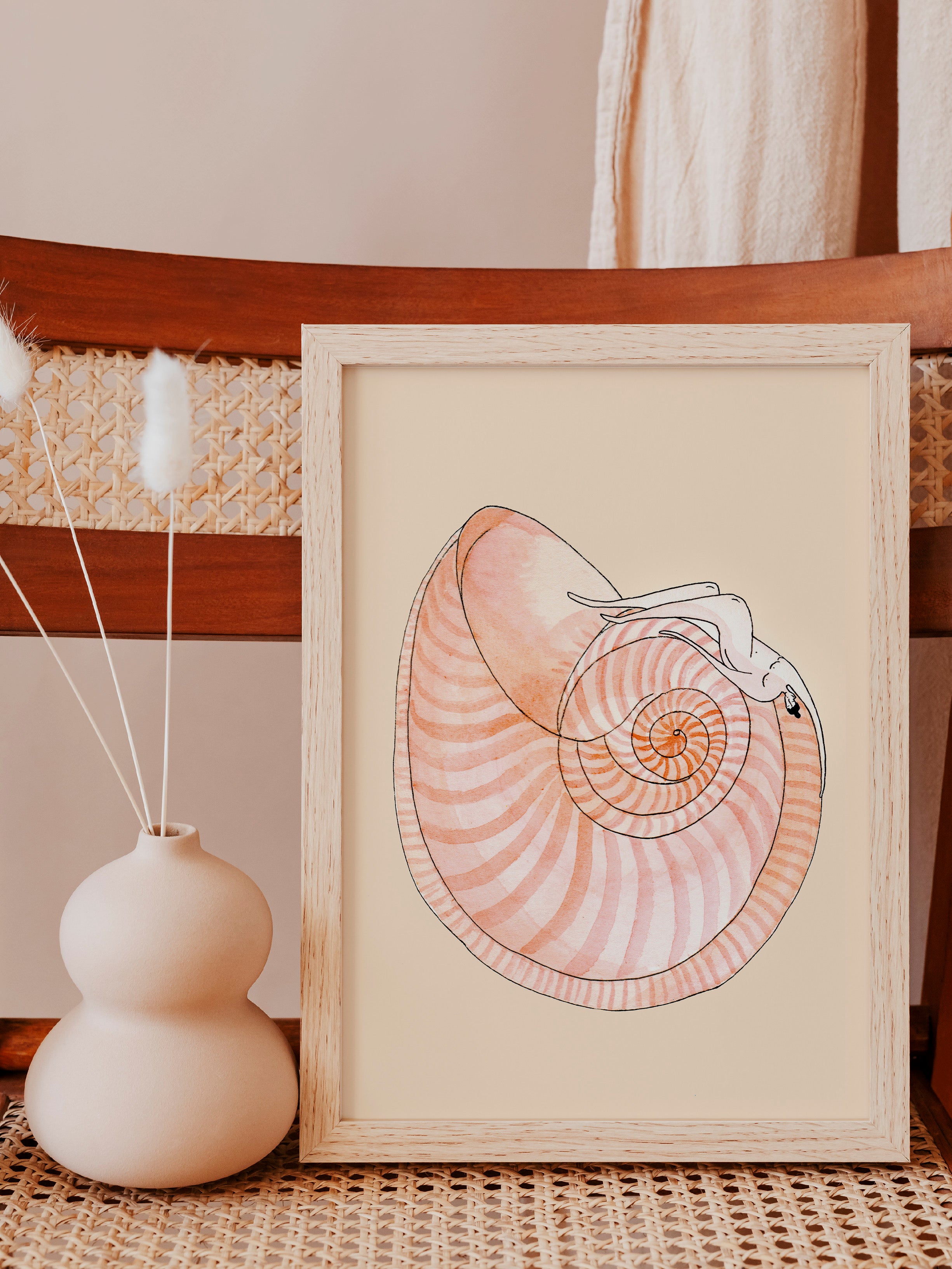 SEASHELL SYMPHONY kunstplakat i hvidpigmenteret træramme på fletstol ved beige vase